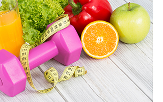 A dumbell and measuring tape in front of fruits and vegetables