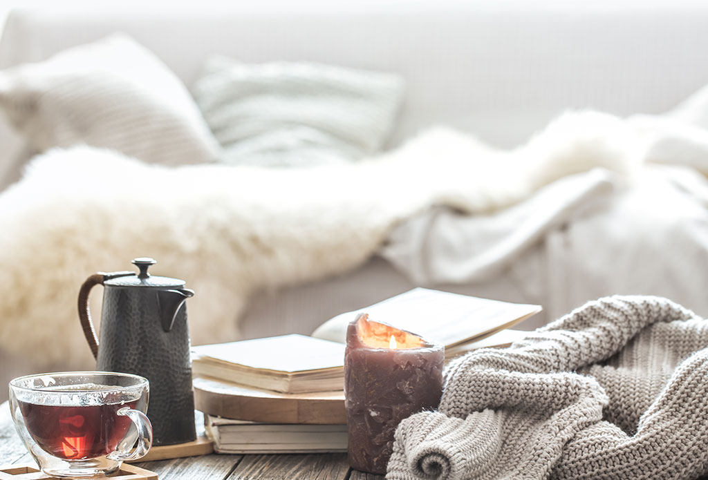 A cozy coffee table with a mug of tea, candle and books