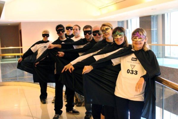 Members of the Sifton staff smiling and dressed up in masks and capes, as superheroes