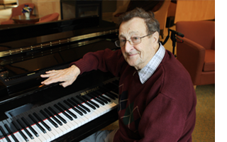An older gentleman sitting in front of a piano