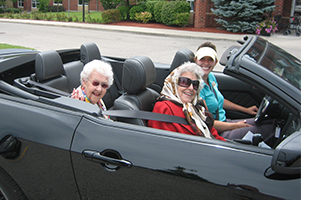 Seniors enjoying a ride in a black convertible.